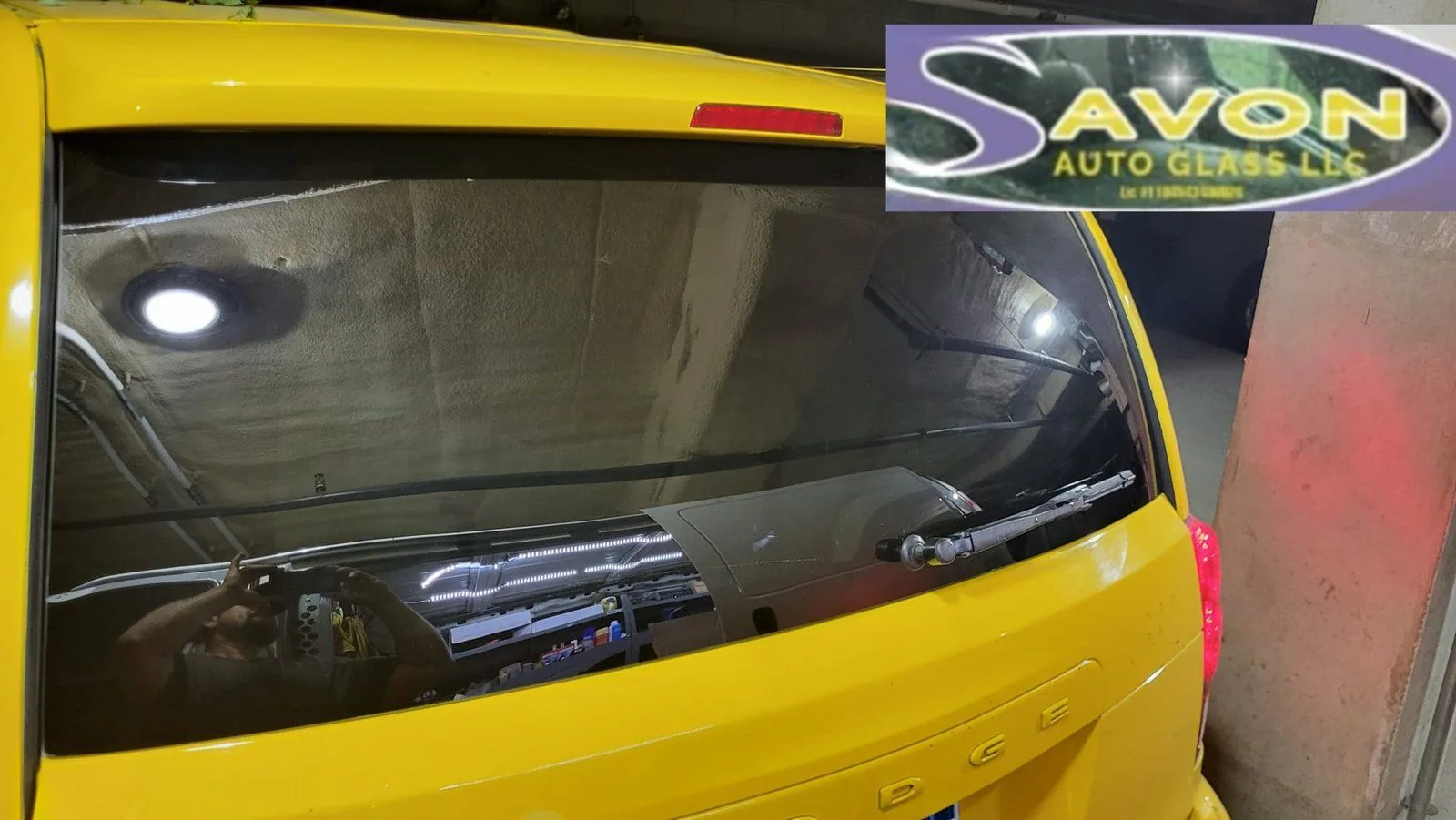 Yellow taxi rear window showing interior dashboard and Avon Auto Glass LLC logo