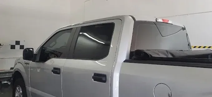 Silver pickup truck with crew cab parked indoors under fluorescent lighting